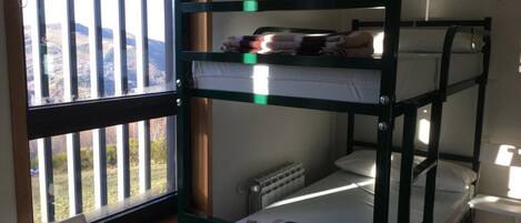 A bunk bed room with a window overlooking a landscape.
