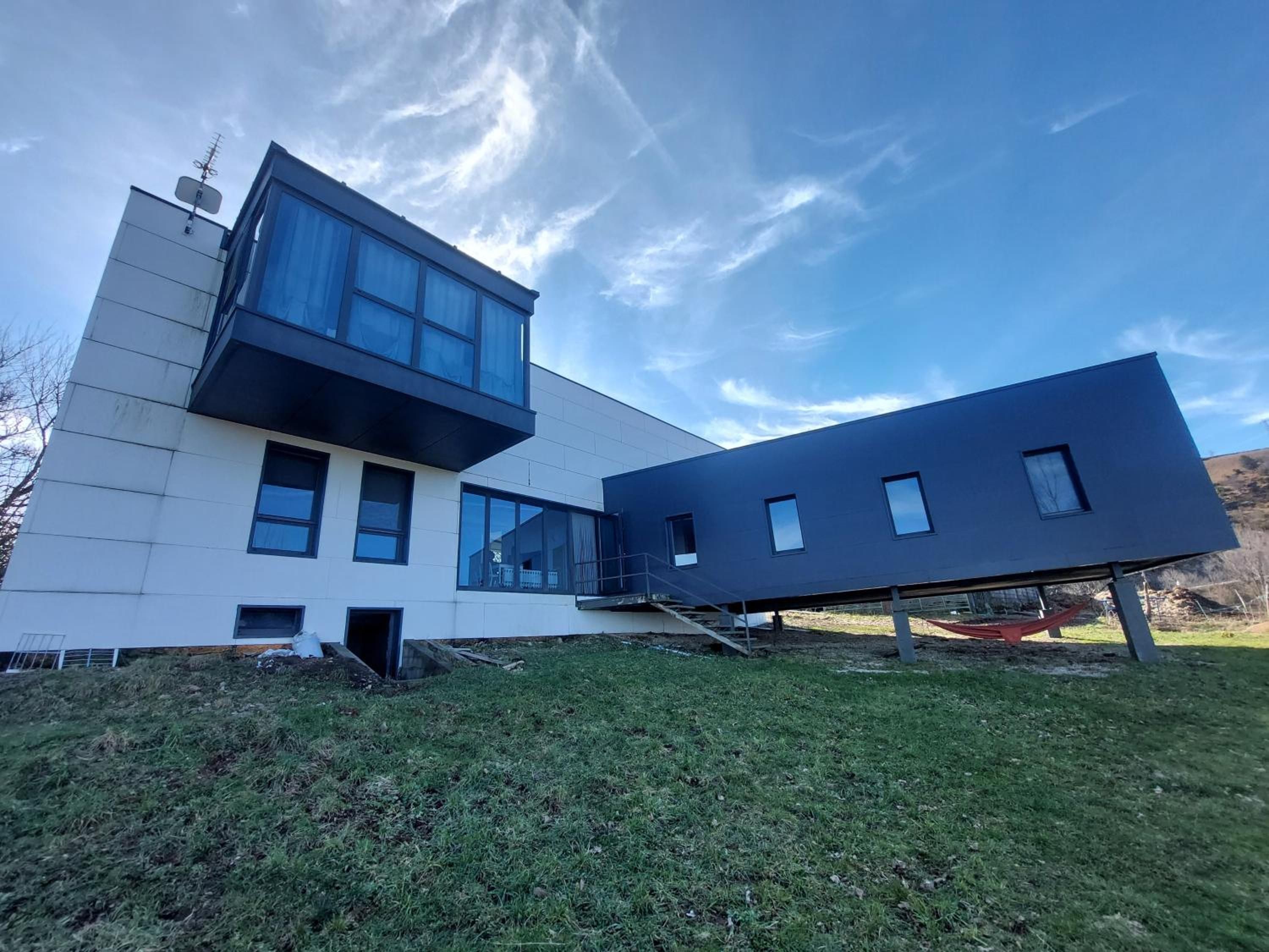 A modern two-story building with a flat roof and large windows.