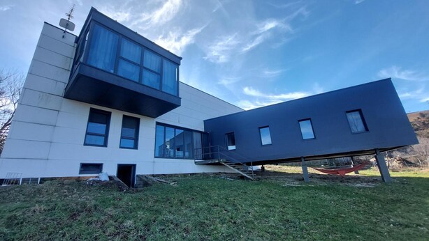 En moderne bygning med to etager, fladt tag og store vinduer.