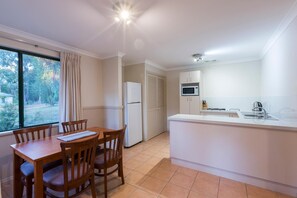 Una cocina compacta con comedor, refrigerador, microondas y pileta.