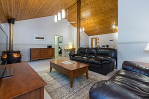 Una sala de estar acogedora con chimenea, sofá de cuero, mesa de centro de madera y un comedor con un armario de madera y un microondas.