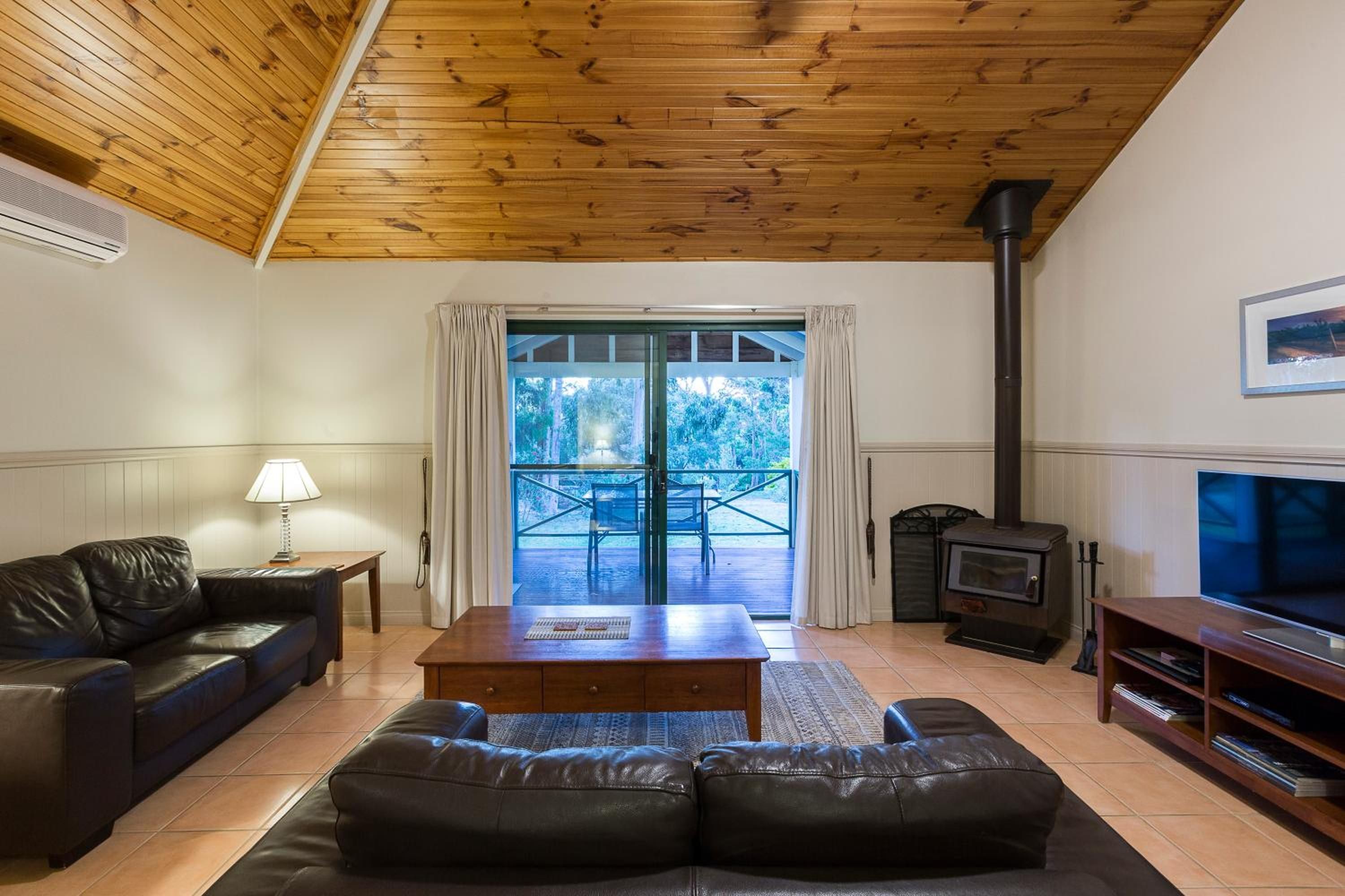 A living room with a leather sofa, a wooden coffee table, a TV stand, and a fireplace.