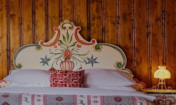 Una cama con un cabecero decorativo, un cojín estampado y una lámpara de noche.