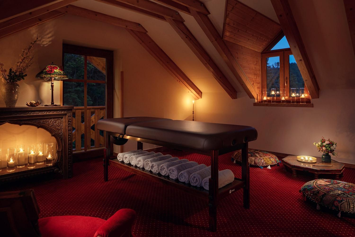 Una habitación con camilla de masaje, velas y ventana con vistas al exterior.