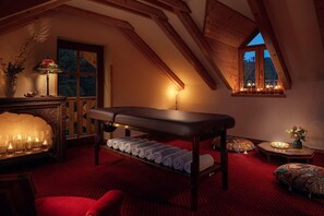Una habitación con camilla de masaje, velas y ventana con vistas al exterior.