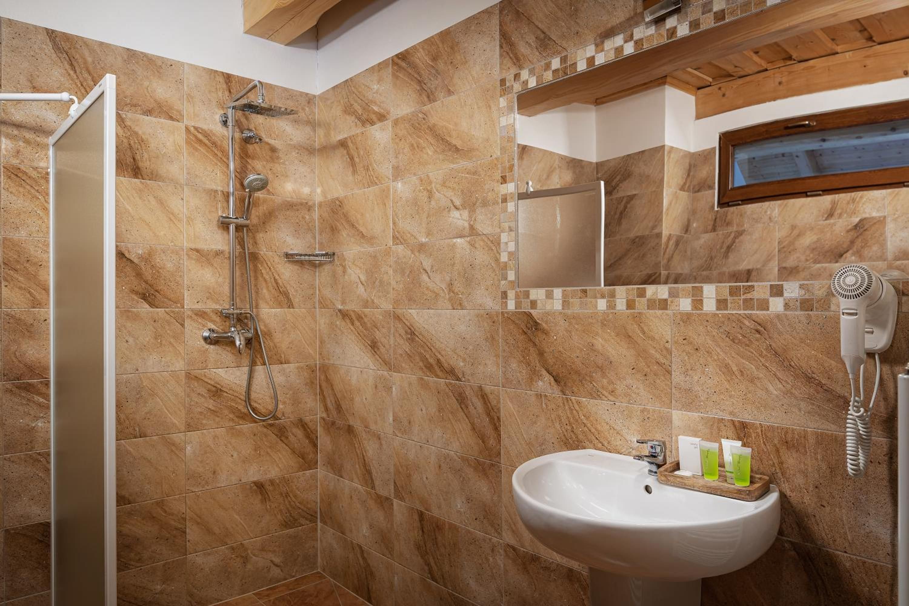 Un baño con ducha, lavamanos y espejo.