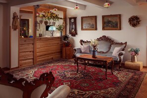 Un salón tradicional con un sofá de madera, un tapiz estampado y una radio antigua.