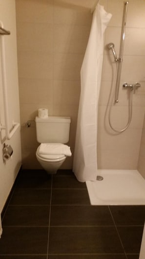 Ein kleines, kompaktes Badezimmer mit Toilette, Dusche und Waschbecken.