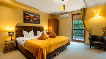 A hotel room with a bed, a nightstand, a chair, an air conditioning unit, and a window with curtains.