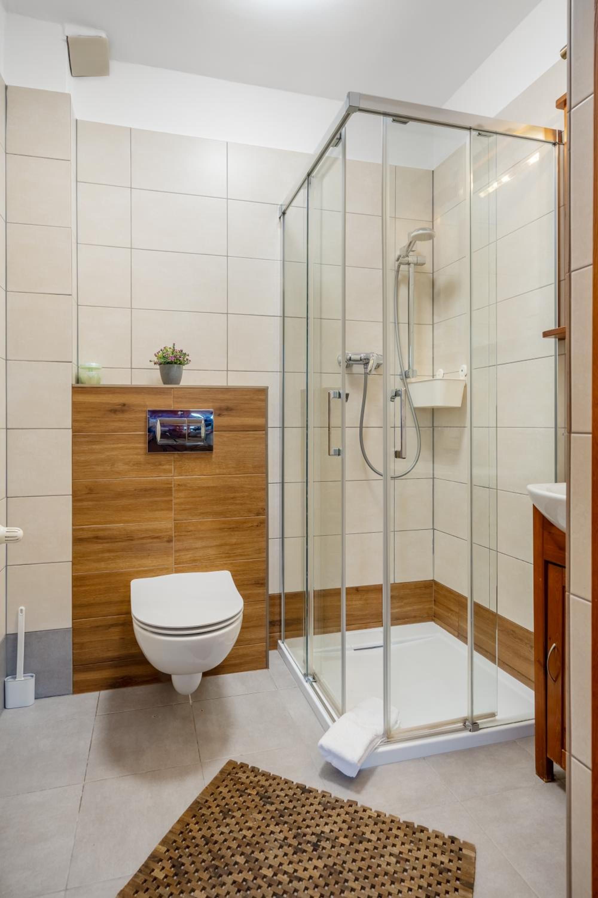 A modern bathroom with a glass-enclosed shower, a toilet, and a wooden vanity.
