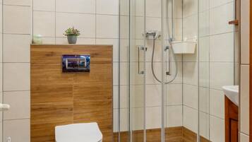 A modern bathroom with a glass-enclosed shower, a toilet, and a wooden vanity.