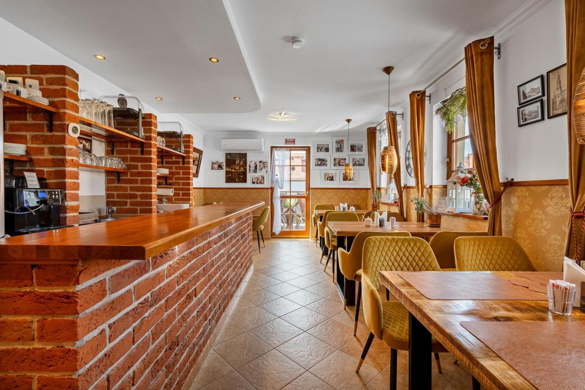 A restaurant interior with brick walls, a bar area, and a dining section with yellow chairs.