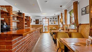 A restaurant interior with brick walls, a bar area, and a dining section with yellow chairs.