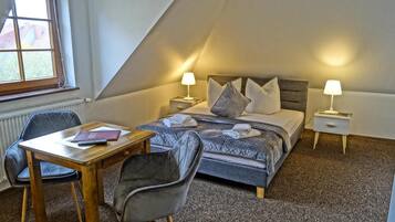 A bedroom with a bed, two bedside tables, a desk, and two chairs.