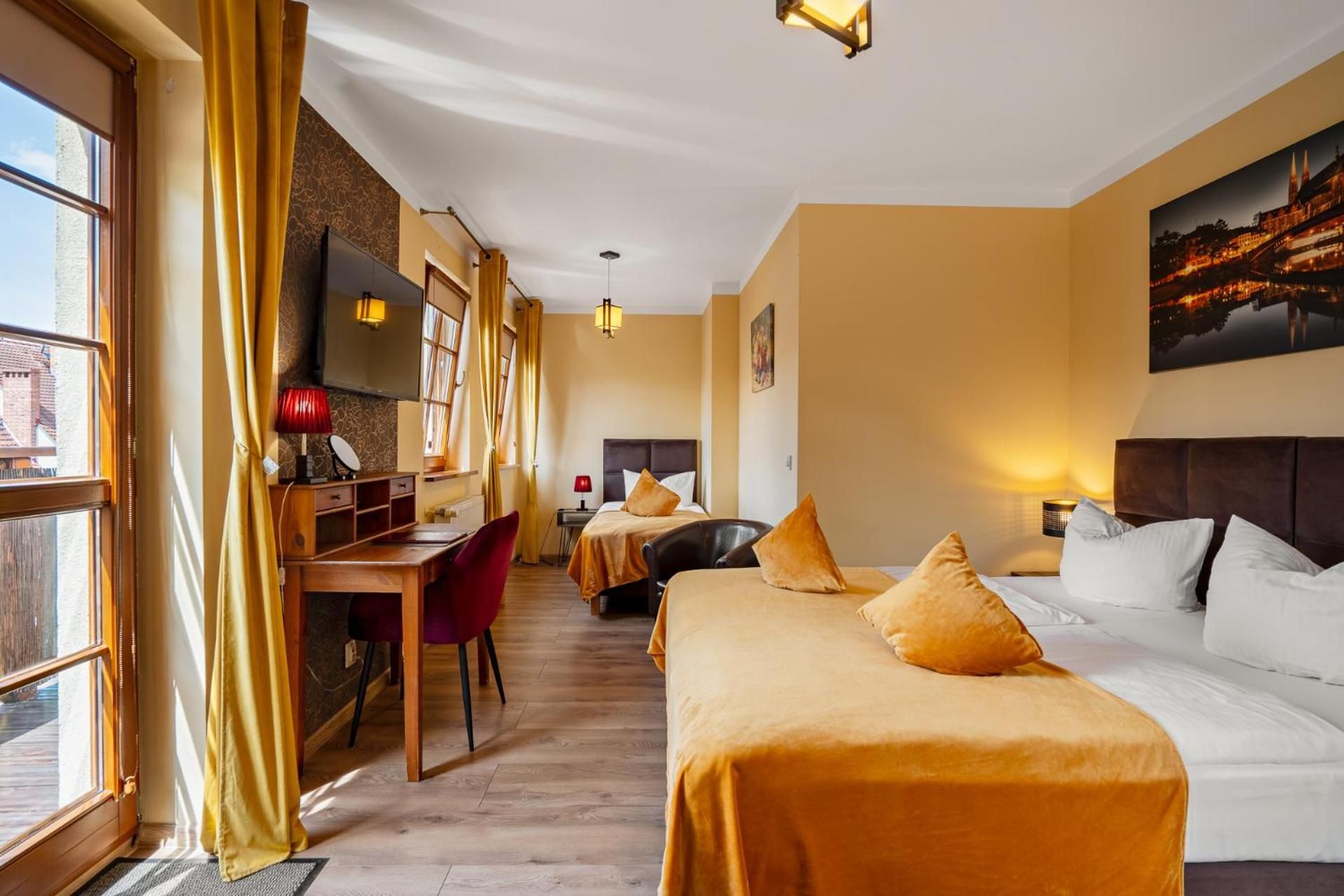 A hotel room with two beds, a desk, a chair, and a large window.