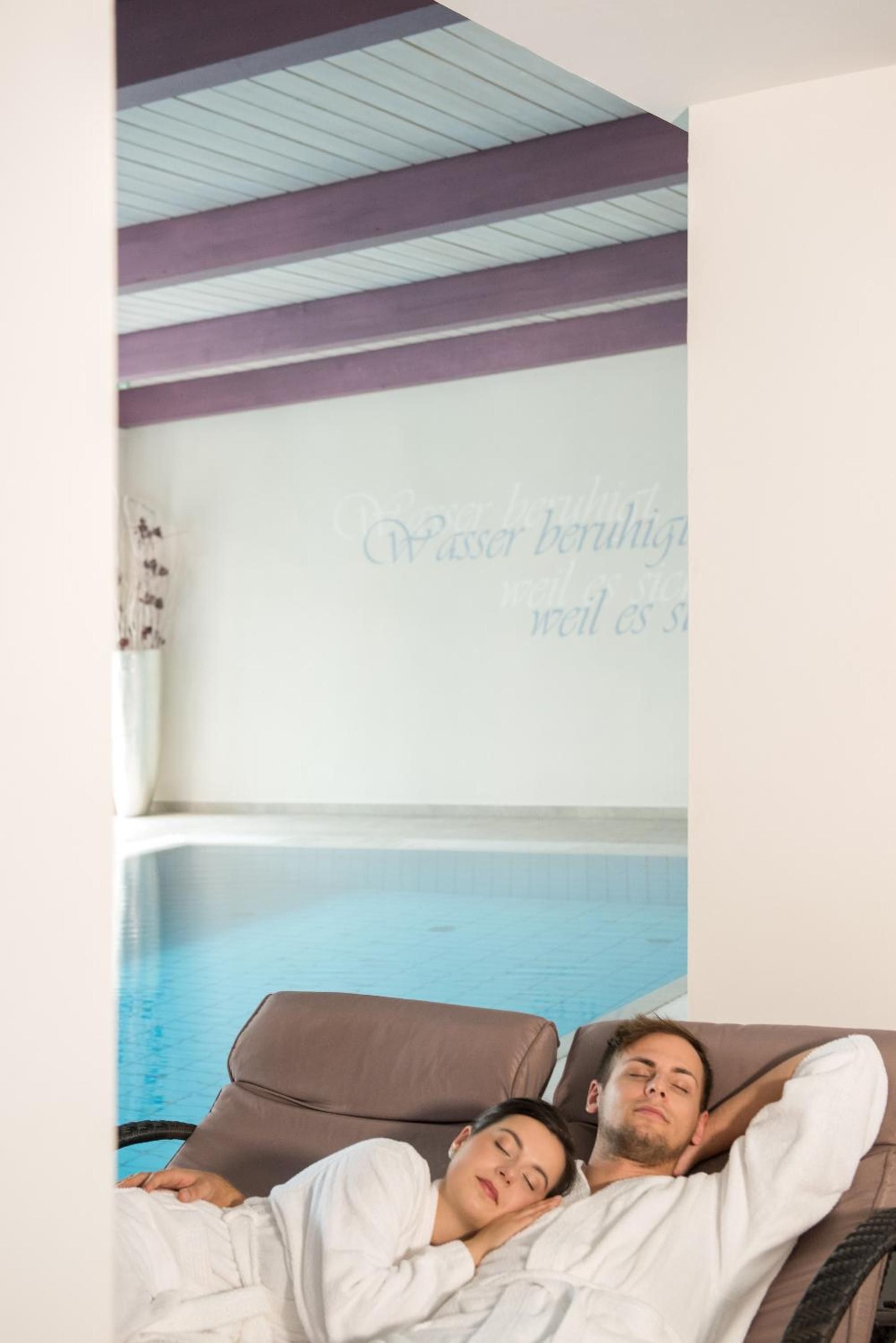 A room with a pool, two reclining chairs, and a wall with a message in a foreign language.