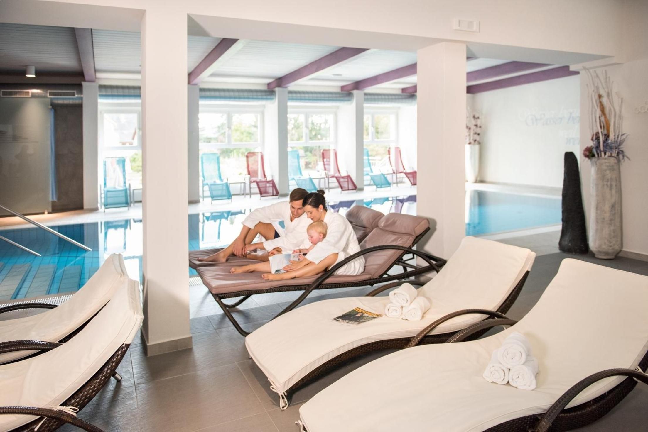 A poolside area with lounge chairs, a pool, and a view of the pool area.