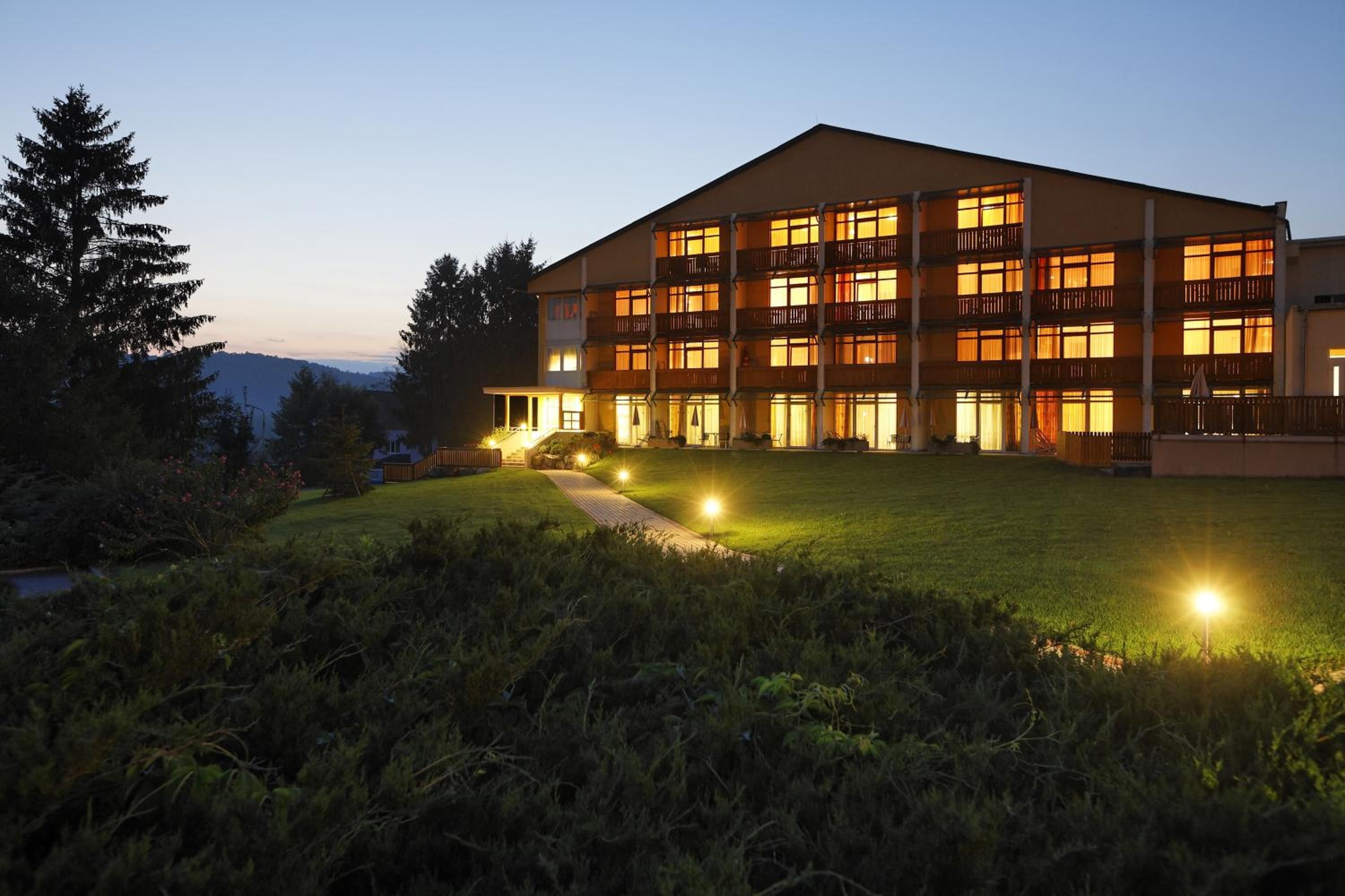 Ein mehrstöckiges Hotel mit flachem Dach, mehreren Balkonen und einem gut beleuchteten Eingang.