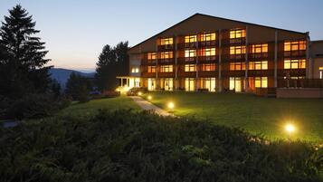 Ein mehrstöckiges Hotel mit flachem Dach, mehreren Balkonen und einem gut beleuchteten Eingang.
