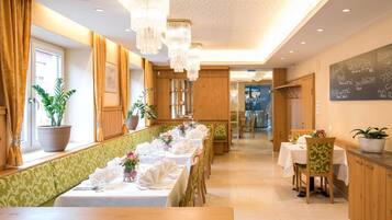 Ein Restaurant mit einem langen Esstisch, der für eine Mahlzeit gedeckt ist, Holzwandverkleidung und einer Kreidetafel als Speisekarte.