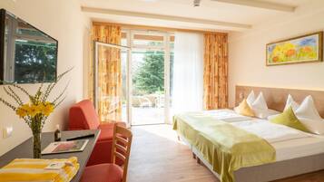 Ein Hotelzimmer mit Bett, Schreibtisch, Stuhl, Wandfernseher und einem Fenster mit Vorhängen.