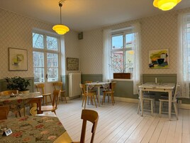 En matplats med bord och stolar i trä, stora fönster och konstverk på väggarna.