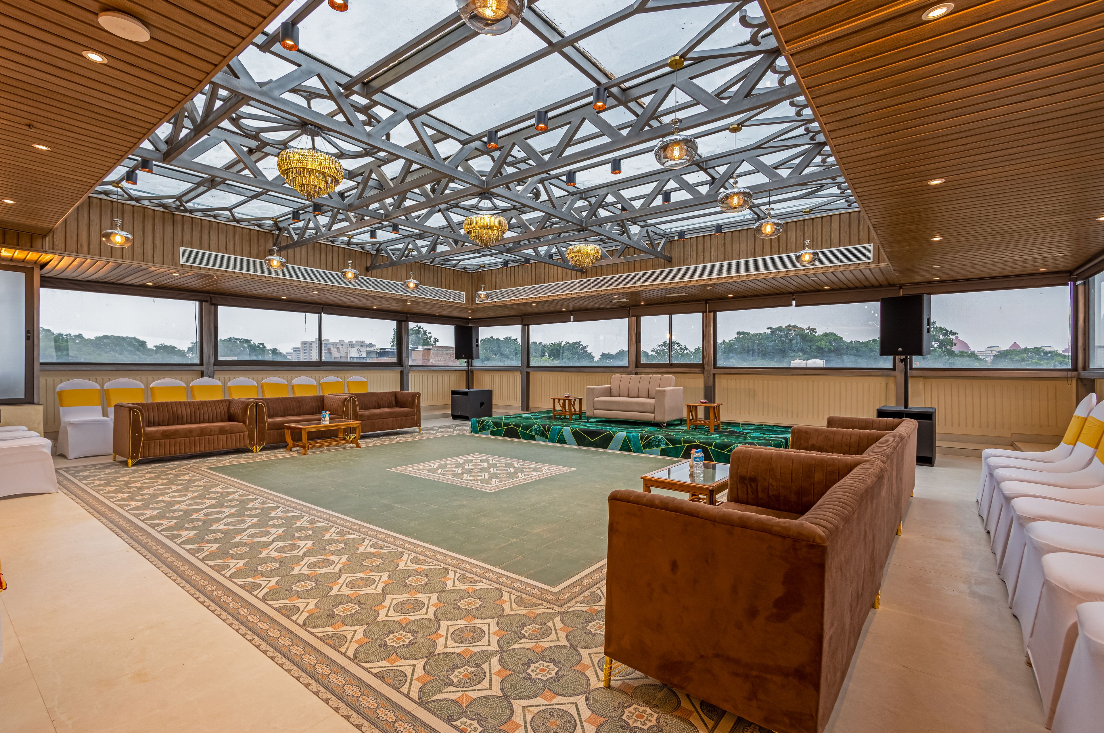 A spacious indoor area with a high ceiling, large windows, and a variety of seating arrangements including sofas and chairs.