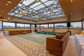 Un espacio interior amplio con techos altos, ventanas grandes y diversas opciones de asientos, incluyendo sofás y sillones.