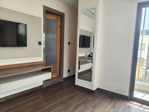 A modern room with a built-in TV, a wooden bench, a mirror, and a balcony view. - Sterling Varanasi (Varanasi)