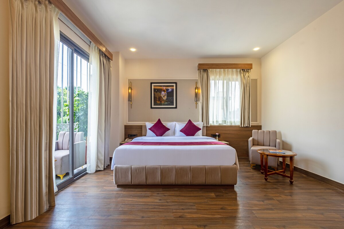 Habitación de hotel con una cama grande, una mesita pequeña, una silla y vistas al exterior.