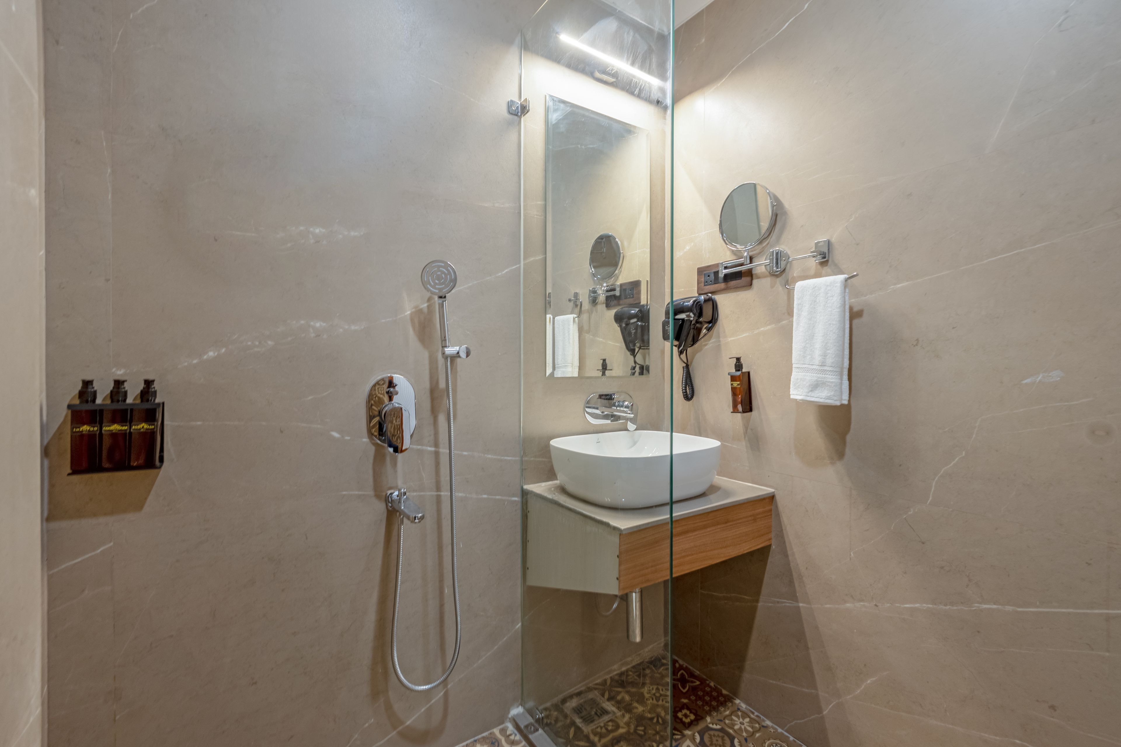 A modern bathroom with a glass shower enclosure, a white sink, and a mirror.