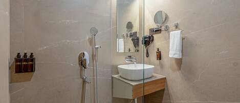 A modern bathroom with a glass shower enclosure, a white sink, and a mirror.