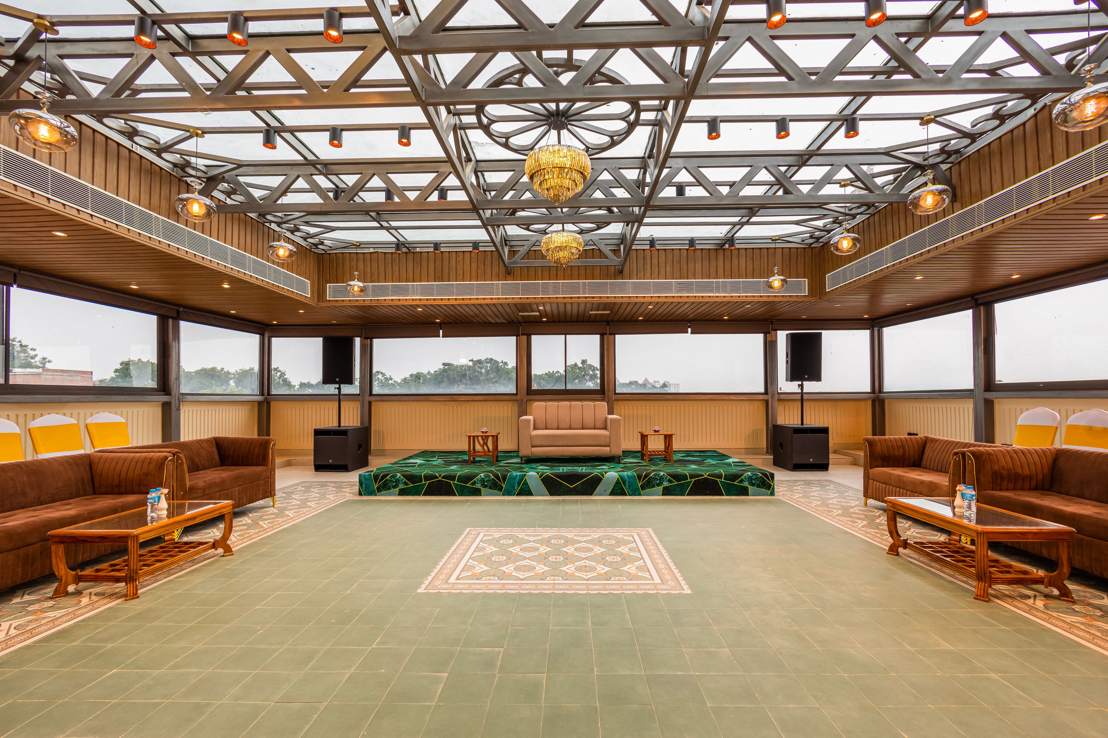 A spacious room with a high ceiling, large windows, and a central seating area with sofas and a coffee table.