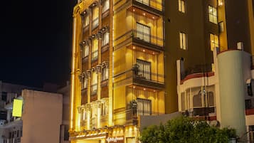 A multi-story hotel with a balcony on the second floor, a sign indicating it is a Sterling Varanasi hotel, and a gated entrance with potted plants.