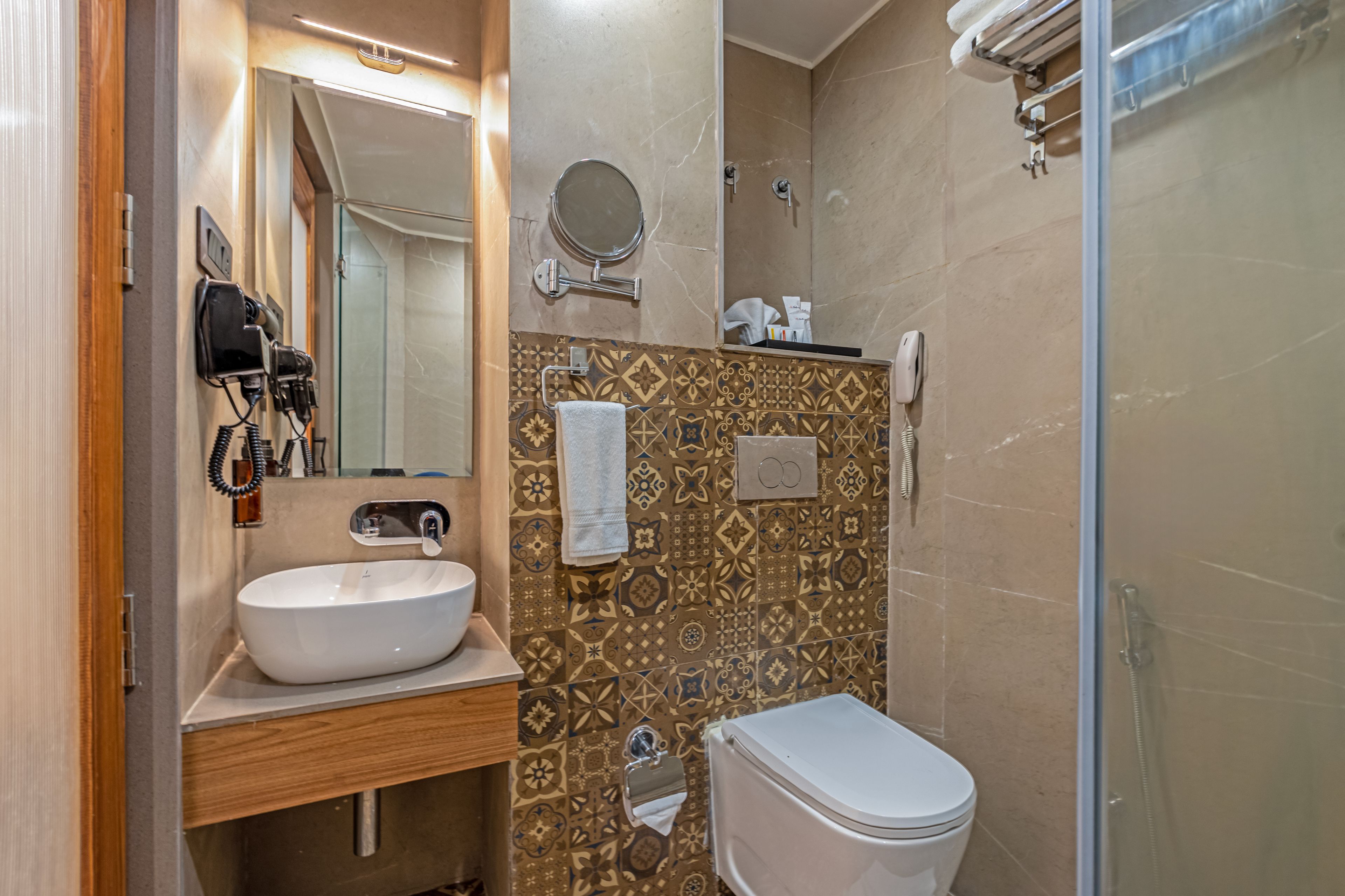 A bathroom with a white sink, a mirror, a toilet, and a shower area.