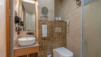A bathroom with a white sink, a mirror, a toilet, and a shower area.