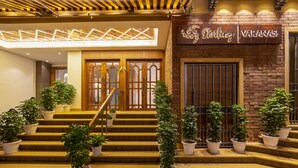 Entrada de hotel com escadaria, plantas em vasos e uma placa com a inscrição 'Sterling Varanasi'.