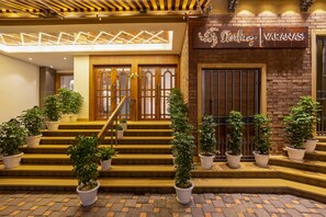 Entrada de un hotel con una escalera, plantas en macetas y un letrero que dice 'Sterling Varanasi'.
