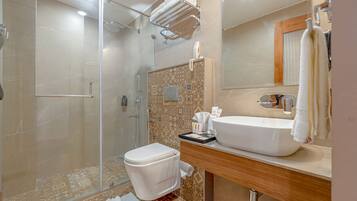 Un baño moderno con cabina de ducha de vidrio, inodoro blanco, lavabo con espejo y perchero para toallas.