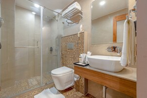 Un baño moderno con cabina de ducha de vidrio, inodoro blanco, lavabo con espejo y perchero para toallas.