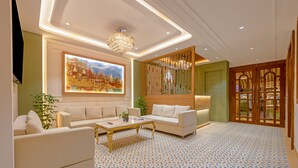 Uma sala de estar moderna com sofá, mesa de centro, lustre e uma grande pintura de paisagem urbana.