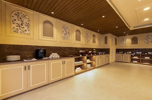 A spacious kitchen with wooden cabinets, marble countertops, and a variety of kitchenware.