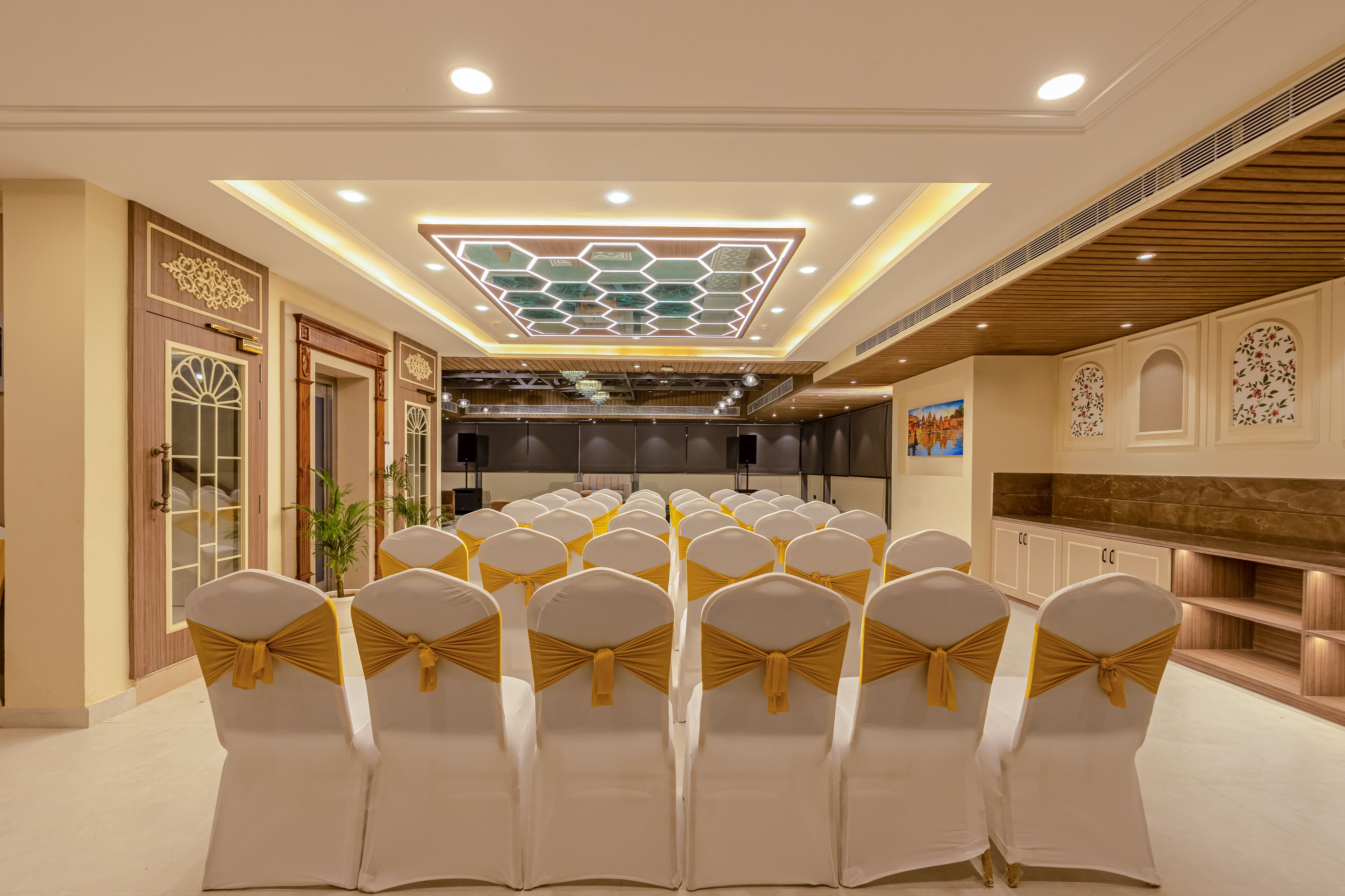 A conference room with rows of chairs, a stage, and a decorative ceiling.