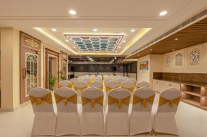 A conference room with rows of chairs, a stage, and a decorative ceiling.