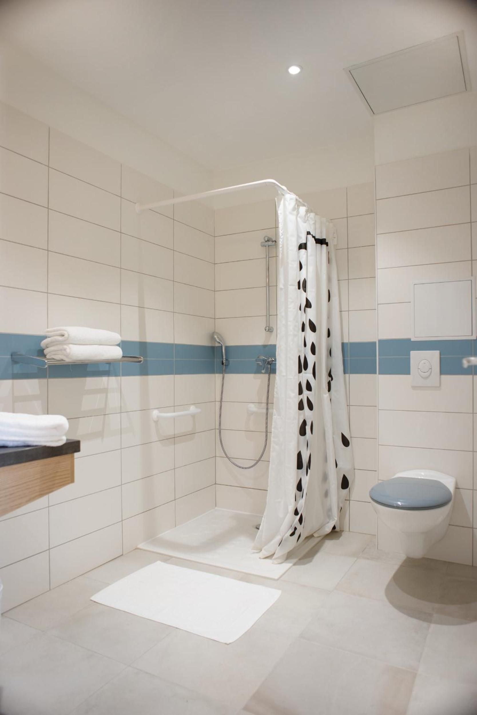 A bathroom with a shower, toilet, and a towel rack.