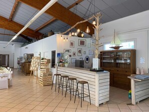 Ein Restaurantinneres mit Holzbalkendecke, einer Bar mit Hockern und einer Präsentation aus Holzkisten.