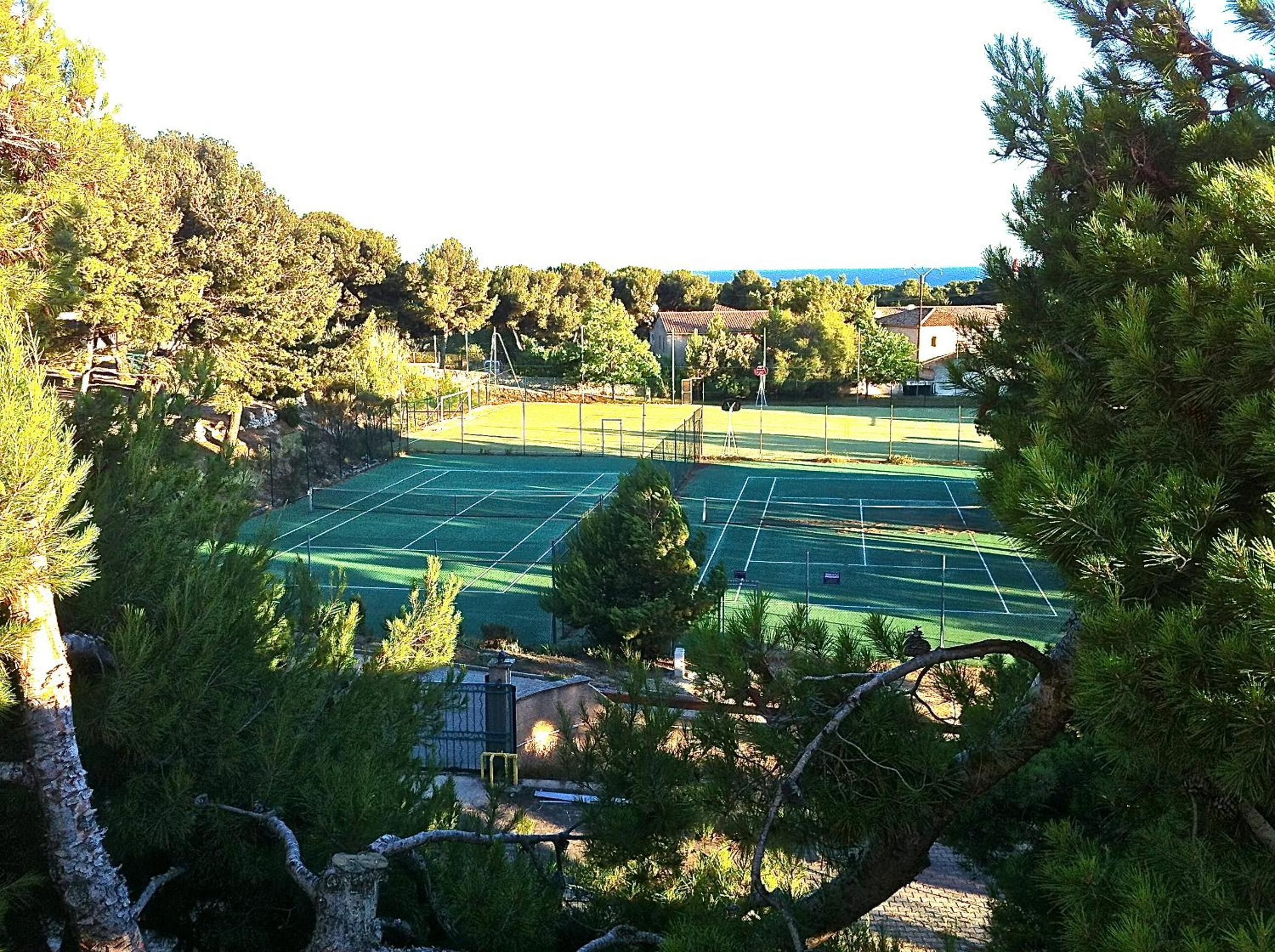 A tennis court surrounded by trees and buildings.