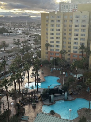 Un hotel con diverse piscine, palme e vista sulla città circostante.