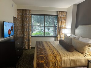 Una habitación de hotel con una cama, un televisor en la pared y una ventana con cortinas.