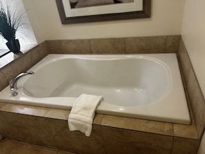Una bañera rectangular con un solo grifo, una toalla colgada a un lado y un cuadro enmarcado encima.